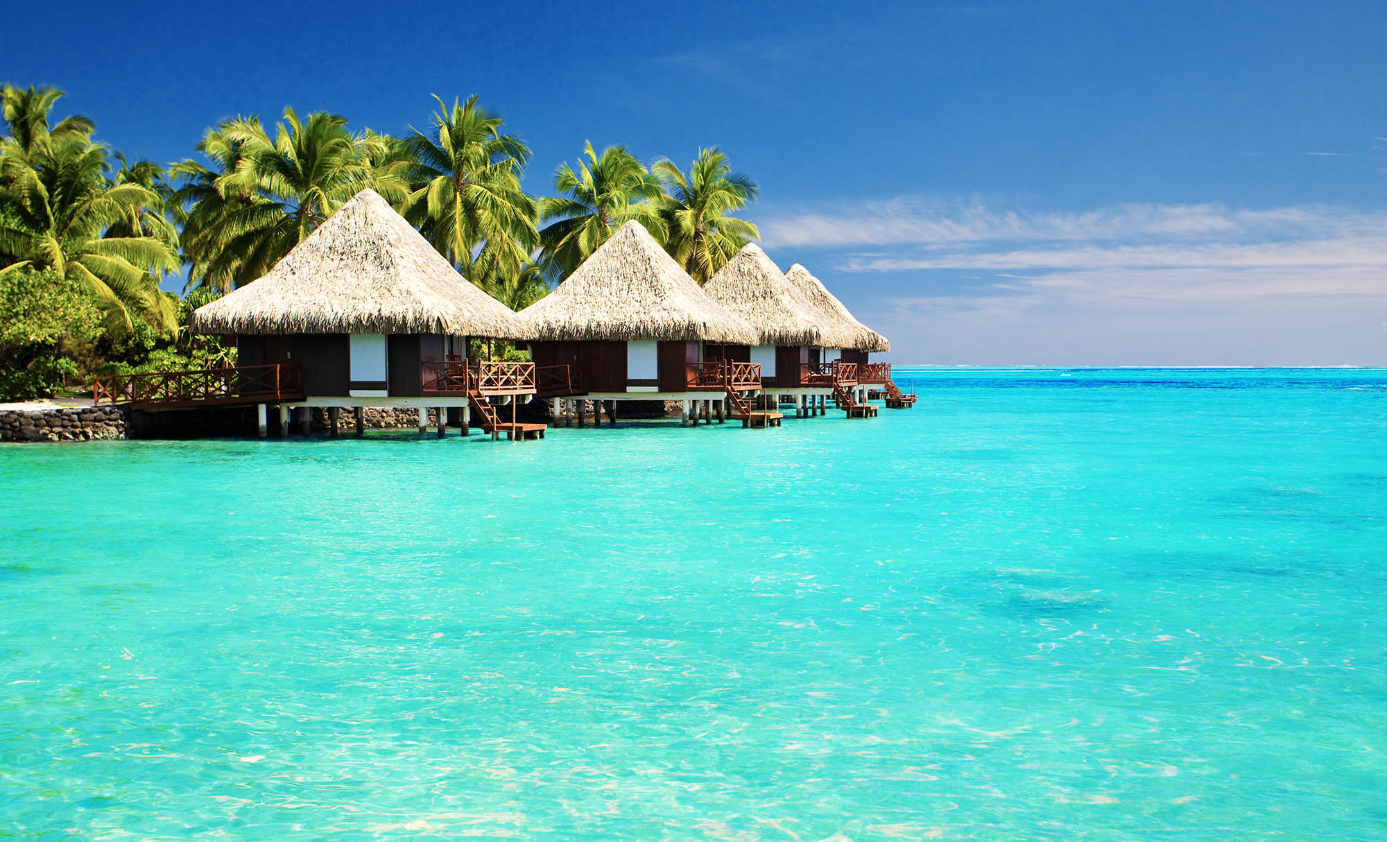 Overwater bungalows on a tropical island with clear turquoise water